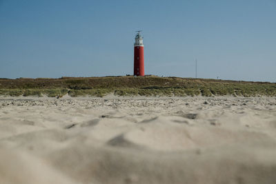 Lighthouse on beach against sky