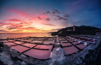 High angle view of salt flats by sea against cloudy sky during sunset