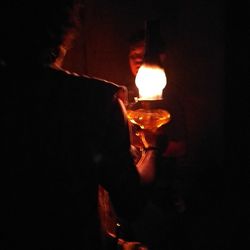 Man holding lit candles in dark room