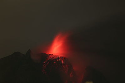 Low angle view of volcanic mountain against sky at night