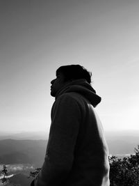 Side view of man looking at mountain against sky