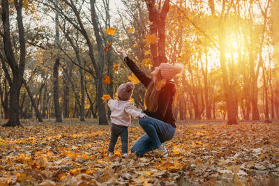 Man and woman standing by trees in forest during autumn