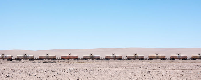 Freight train on desert against clear blue sky