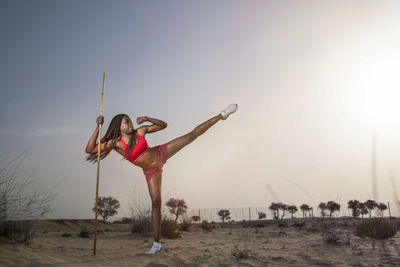 Full length of woman exercising in desert against sky