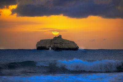 Scenic view of rock on sea against sky during sunset