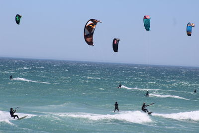 People kiteboarding in sea against sky