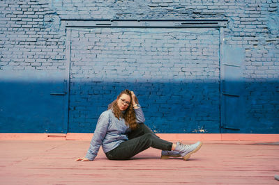 Portrait of young woman sitting on wall