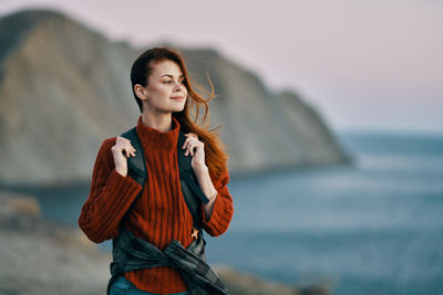 Young woman standing by sea against sky