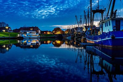 Boats moored in river at harbor against blue sky