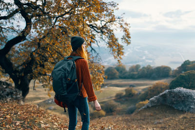 Rear view of woman standing on rock against sky