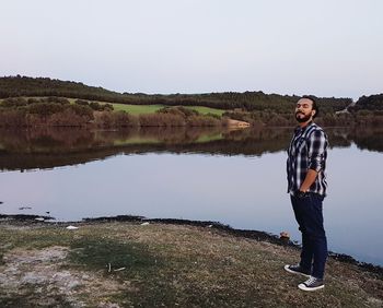 Portrait of young man standing on lake against sky