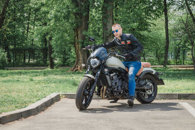 Man riding motorcycle on road against trees