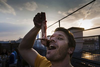 Funny man holding a piece of raw meat on mouth