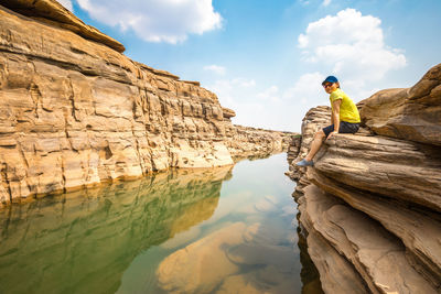 People standing on rock formation against sky