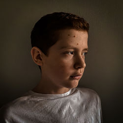 Boy looking away against wall at home