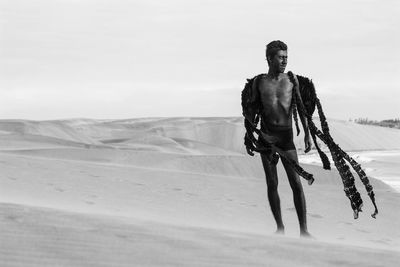 Teenage boy in costume on desert against sky