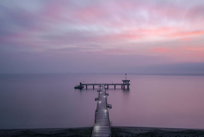 Pier over sea against sky during sunset