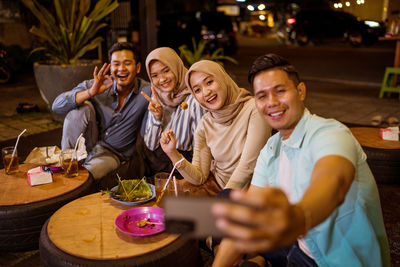 Portrait of smiling friends sitting at restaurant