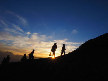 Silhouette people standing on mountain against sky during sunset