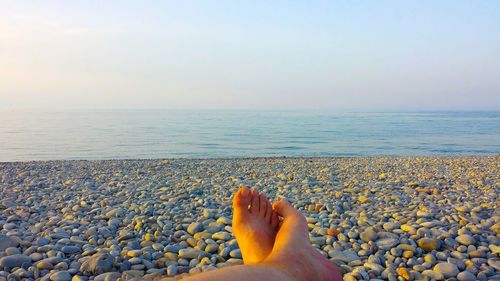 Low section of woman on beach against clear sky