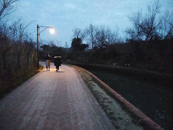 Rear view of people walking on street against sky