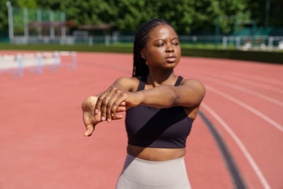 African american female stretches hands warming up before intensive workout on sunny summer day