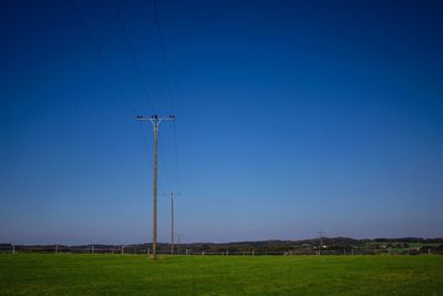 Trees on landscape against clear blue sky