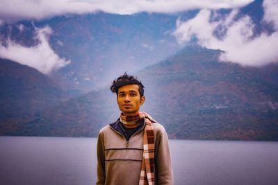 Portrait of young man standing in mountains against sky