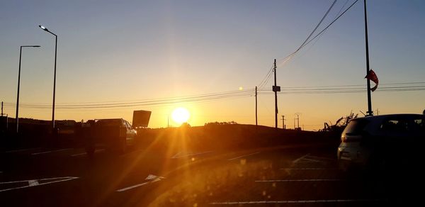 Cars on street against sky during sunset