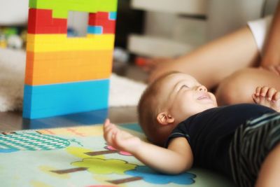 High angle view of baby boy relaxing on the floor near colored toys