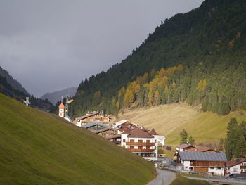 Houses on field by mountains against sky