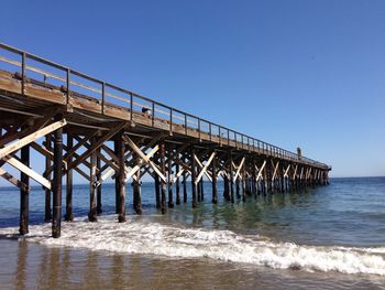 Pier over sea against clear blue sky