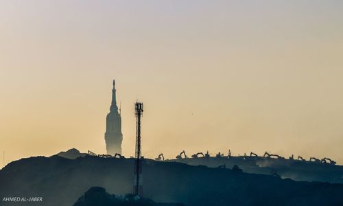 Smoke stack by building against sky during sunset