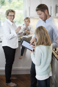Family using digital tablet while cooking in kitchen