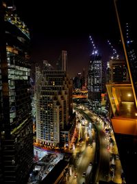 High angle view of illuminated street amidst buildings in city at night