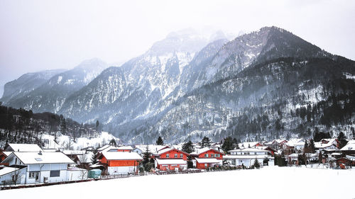 Snow covered houses and mountains against sky