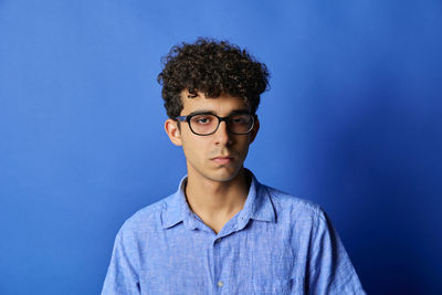 Portrait of young man standing against blue background