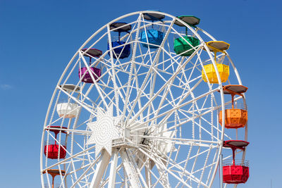 Low angle view of ferris wheel against clear blue sky