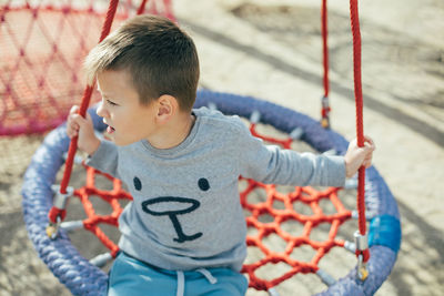 Full length of cute boy holding slide in playground