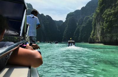 People on boat against mountain range