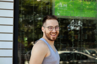 Portrait of smiling young man standing against window