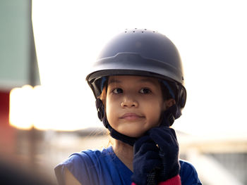 Close-up of girl wearing helmet looking away against clear sky