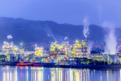 Illuminated industrial district by river at night