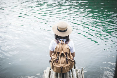 Rear view of woman sitting by lake