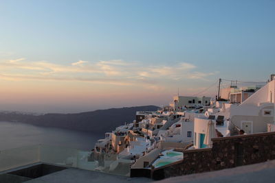 High angle view of buildings by sea against sky during sunset