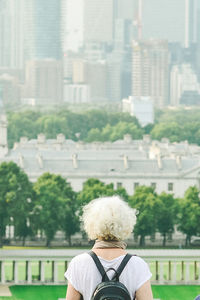 Rear view of woman with umbrella against building