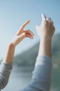 Midsection of woman with arms raised against sky