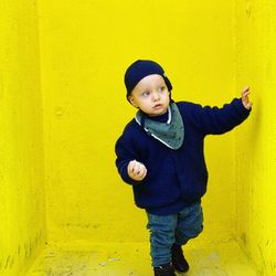 Portrait of boy standing against yellow wall