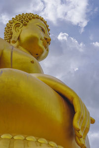 Low angle view of yellow statue against sky