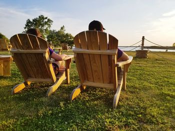 Men sitting on grass against sky